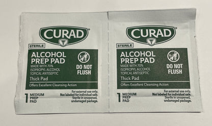 Two Curad Sterile Alcohol Prep Pad single-use packets on a plain white surface.