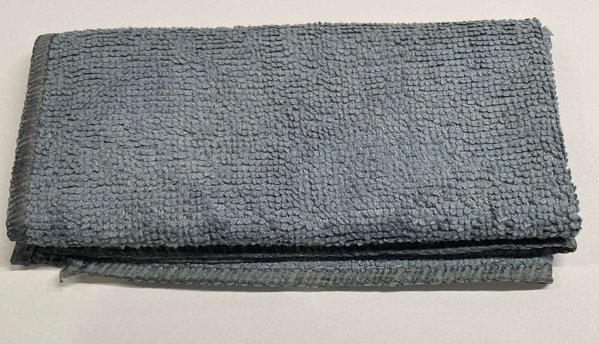 A folded gray microfiber cleaning cloth with a textured, looped terry-like surface, shown on a plain off-white background.
