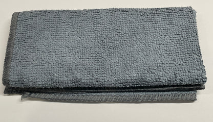 A folded gray microfiber cleaning cloth with a textured, looped terry-like surface, shown on a plain off-white background.